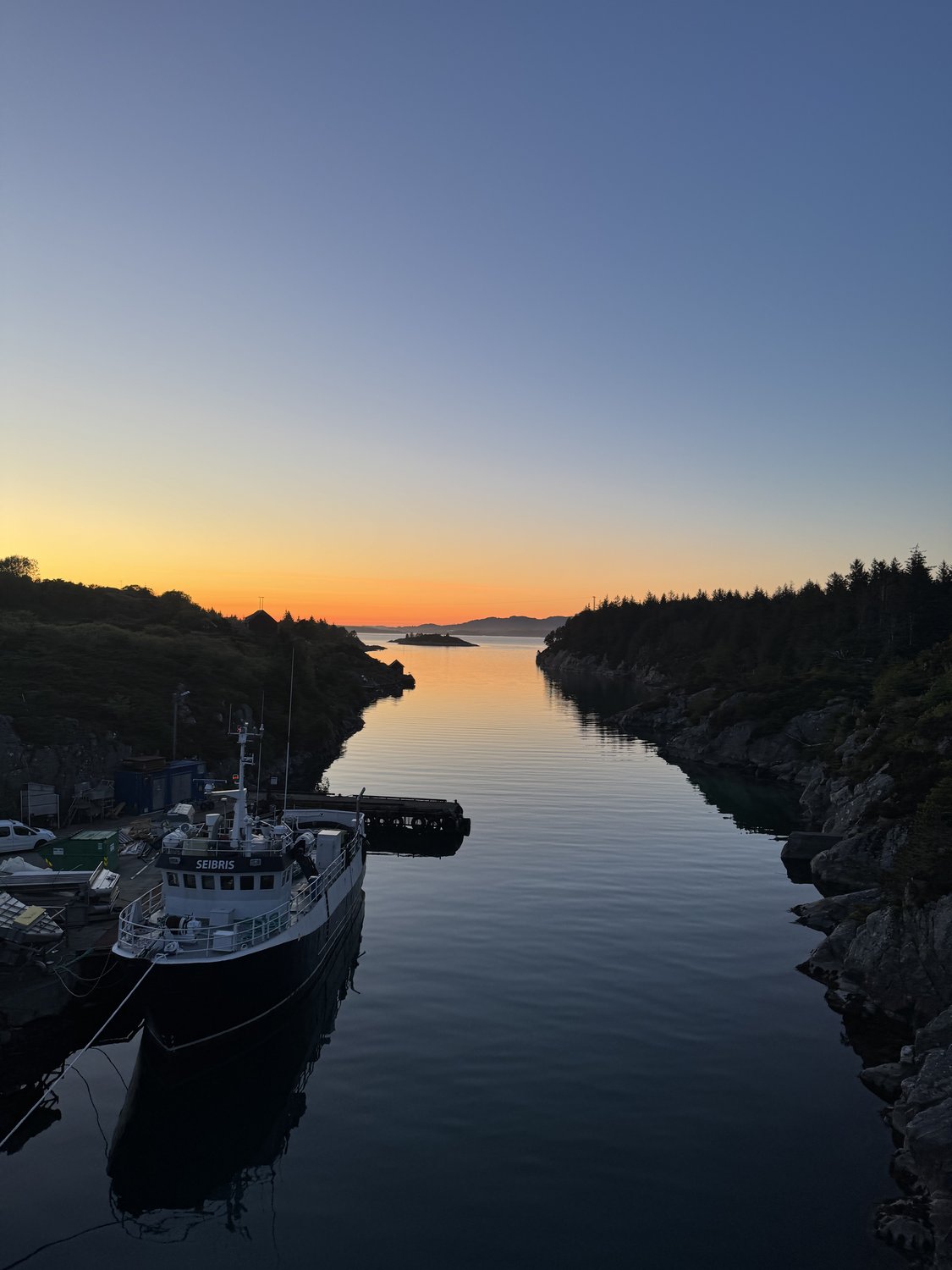 A working vessel on the fjord at sunset